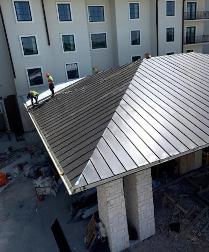 Crew installing standing seam metal roof panels on a commercial project in Overland Park